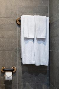 un grupo de toallas blancas colgando en una ducha en Къщи за гости Сноуфлейк Snowflake Chalet and Snowflake Lodge, en Bansko