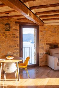 ein Esszimmer mit einem Tisch und einem großen Fenster in der Unterkunft Casa Sanui. Apartaments turístics rurals in Estorm