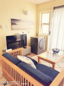 ein Wohnzimmer mit einem Sofa und einem Flachbild-TV in der Unterkunft Kapenta Bay Unit 31 Holiday Resort-Port Shepstone in Port Shepstone