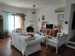 a living room with white furniture and a fireplace at C & C _ Cycladic house with endless sea view in Ermoupoli