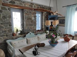 a dining room with a table and a stone wall at C & C _ Cycladic house with endless sea view in Ermoupoli