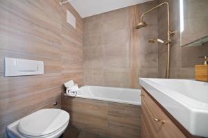 a bathroom with a toilet and a tub and a sink at Charmant studio rénové situé dans les bains d'Ovronnaz, immeuble les Sources in Ovronnaz