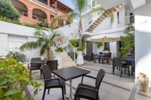 an outdoor patio with tables and chairs and palm trees at Hotel Belvir in Villasimius