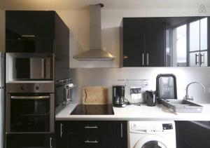 une cuisine avec des placards noirs, un lave-linge et un évier dans l'établissement Mairie de Saint-Ouen (Métro 13/14), à Saint-Ouen