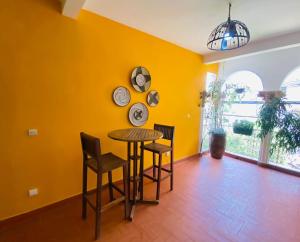 d'une salle à manger avec une table, des chaises et un mur jaune. dans l'établissement ILLIYIN Boutique Hotel, à Dakar