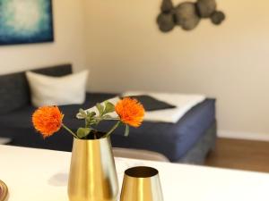 twee gouden vazen met oranje bloemen op een tafel bij Saarland Appartements in Wadgassen