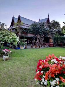 ein Haus mit Blumen davor in der Unterkunft MrT Riverside Sampran มิสเตอร์ที โฮมสเตย์-การเวก in Sam Phran