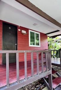 une maison rouge avec une terrasse en bois dans l'établissement MrT Riverside Sampran มิสเตอร์ที โฮมสเตย์-การเวก, à Sam Phran