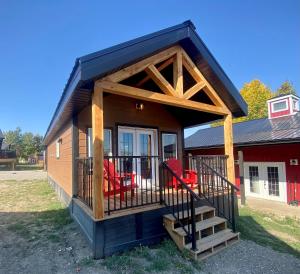 a tiny house with a porch and red chairs at Stardust Inn and Chalets in Pincher Creek