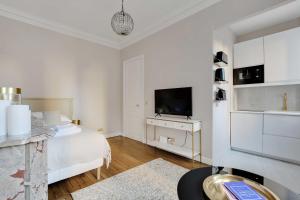 ein weißes Schlafzimmer mit einem Bett und einem TV in der Unterkunft Charming Studio - 2P Villiers in Paris
