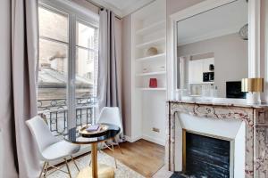 ein Wohnzimmer mit einem Kamin, einem Tisch und Stühlen in der Unterkunft Charming Studio - 2P Villiers in Paris