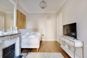 ein weißes Schlafzimmer mit einem Bett und einem Kamin in der Unterkunft Charming Studio - 2P Villiers in Paris