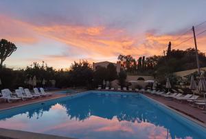 una piscina con sedie e un tramonto di Residence Esmeraldo a Capo Vaticano