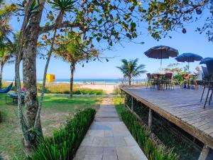 eine hölzerne Promenade, die zu einem Strand mit Tischen und Sonnenschirmen führt in der Unterkunft Spazio Marine Hotel - Guaratuba in Guaratuba