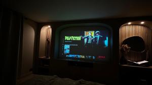 einen TV in einem dunklen Zimmer mit einem TV-Bildschirm in der Unterkunft Maison Nina, Suite d’exception in Villeneuve-la-Garenne