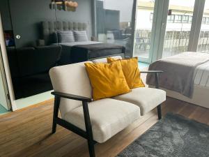 a chair with yellow pillows sitting in a room at NiP Apartment | Porto City Center Near All Sights in Porto