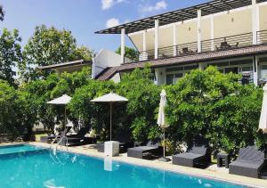 a swimming pool with umbrellas and chairs next to a building at Atteriya SIGIRIYA in Sigiriya