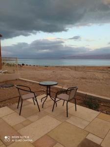 a table and two chairs on a patio near the beach at A romantic zimmer on the dead sea in Ovnat