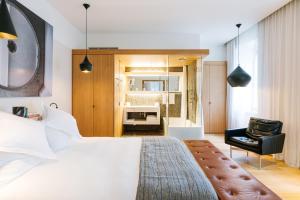 a bedroom with a large white bed and a chair at B2 Hotel Zürich in Zurich