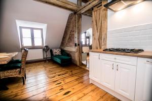 a kitchen with white cabinets and a wooden floor at AP Apartment's in Wałbrzych