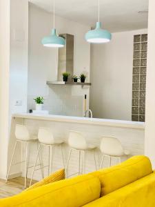 kuchnia z żółtą kanapą i blatem ze stołkami w obiekcie Flamenca Triana - Apartamento Totalmente Equipado Wifi 2D sofas camas 2 baños w Sewilli