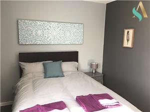 比林罕的住宿－South View TSAC，一间卧室配有一张带紫色和蓝色枕头的床