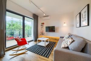 a living room with a couch and a red chair at Wellness Apartamenty Złoty Widok in Szczyrk