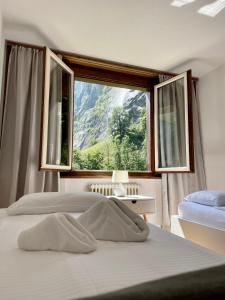 sypialnia z 2 łóżkami i dużym oknem w obiekcie Breathtaking Waterfall Apartment w mieście Lauterbrunnen