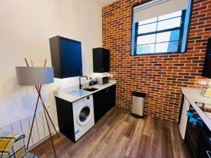 a washing machine in a room with a brick wall at Apartment 8 Sullivan House in Hereford