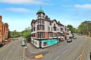 a large white building with a green turret on a street at Finest Retreats - Sunnycroft Penthouse in Llandrindod Wells
