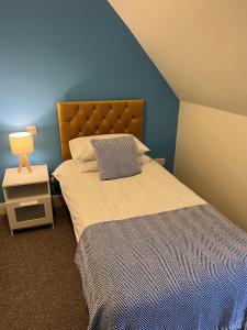 um quarto com uma cama com uma parede azul em The Corrie Hotel em Corrie