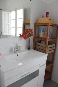 a bathroom with a white sink and a vase with red flowers at FLORIT FLATS - The Ausias March Apartment in Valencia
