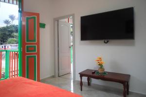 Zimmer mit einem TV an der Wand und einem Tisch in der Unterkunft Hotel Casa Quinta Salento in Salento