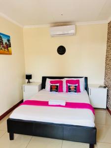 a bedroom with a large bed with pink pillows at Lamamie guest house in Thohoyandou