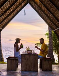 een man en een vrouw aan een tafel op het strand bij Lazy Day The Resort in Ko Mak