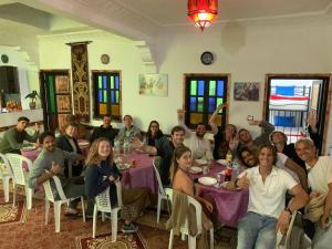 grupa ludzi siedzących przy stole w pokoju w obiekcie Orca Surf House w mieście Taghazout