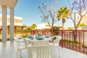 un tavolo bianco e sedie su un patio con recinzione di Appartamento Orchidea A1 - MyHo Casa a Torre Canne