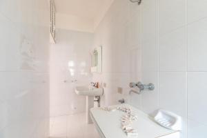 un bagno bianco con lavandino e vasca di Appartamento Orchidea A1 - MyHo Casa a Torre Canne