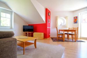 uma sala de estar com uma mesa e uma parede vermelha em Wilhelmstr-10-Whg-25 em Ahlbeck