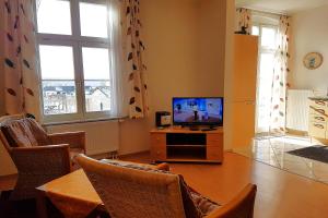 a living room with a television and a table with chairs at Bellevue-App-05 in Ahlbeck