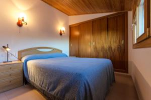 1 dormitorio con 1 cama azul y armario de madera en Maia Pedrous, en Pas de la Casa