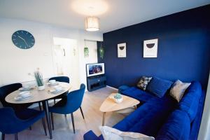 ein Wohnzimmer mit einem blauen Sofa und einem Tisch in der Unterkunft Ideal Lodgings in Whitefield Radcliffe in Manchester