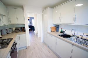 eine Küche mit weißen Schränken und einem Waschbecken in der Unterkunft Ideal Lodgings in Whitefield Radcliffe in Manchester