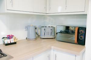 eine Küchentheke mit zwei Toastern und einer Mikrowelle in der Unterkunft Ideal Lodgings in Whitefield Radcliffe in Manchester