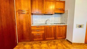 a kitchen with wooden cabinets and a sink at Appartamento Smith Erbaluce - Affitti Brevi Italia in Bardonecchia