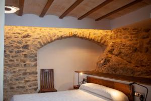 Cama en habitación con pared de piedra en Casa Sanui. Apartaments turístics rurals en Estorm