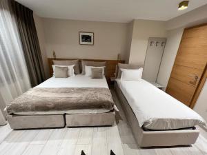due letti in una camera d'albergo con lenzuola bianche di Albergo Aida a Lussemburgo