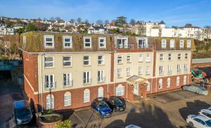 a large brick building with cars parked in a parking lot at The Seaview Suites and Ground Floor Suite at The Corbyn Apartments in Torquay