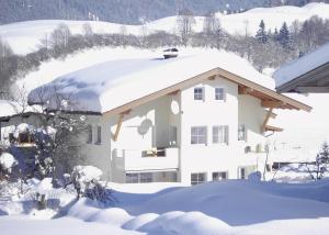 una casa cubierta de nieve con techo cubierto de nieve en Appartement Juffinger, en Thiersee