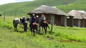 a group of people riding horses in front of a hut at Libibing chalets in Mokhotlong